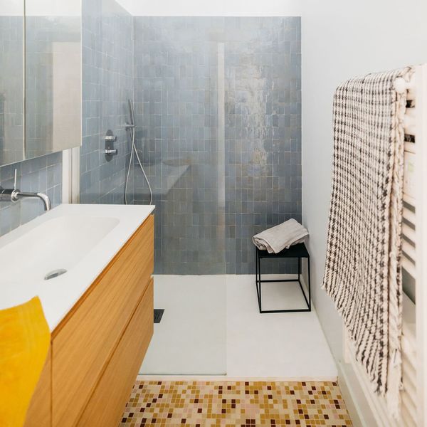 Une grande douche ouverte au bout d'une salle de bains étroite