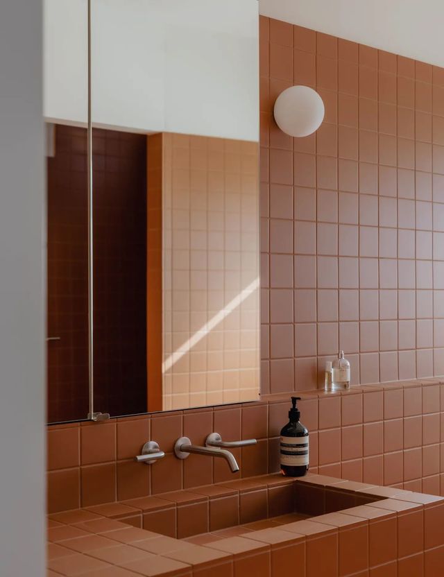 Avec un grand miroir, le rose s'amuse avec les reflets dans une petite salle de bains.